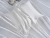 A white silk pillowcase is laid out on a white silk sheet, with a magazine and a cup of coffee in the upper left corner. Podgląd zdjęcia produktu