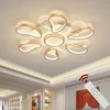 A modern ceiling lamp with petal-like elements, shown in a room setting with a remote control. Podgląd zdjęcia produktu