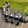 A couple is enjoying a meal at a dining table set up on a wooden deck in a garden. Náhled obrázku produktu