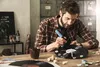 A man is crafting a clock from a vinyl record, using a glue gun. Produktbild-Vorschau