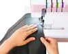 A person's hands are shown guiding gray fabric through a pink and white overlock sewing machine. Produktbild-Vorschau