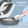 A hand is scooping cat litter from a cat litter box with a scoop. The litter box is open, showing the litter inside and arrows indicating ventilation. Náhled obrázku produktu