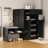 A black shoe cabinet with a built-in bench and storage compartments, shown in a home entryway setting. Produktbild-Vorschau