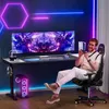 A man is sitting in a gaming chair in front of a gaming desk with dual monitors, holding a game controller. Voir les images du produit