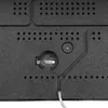 A close-up view of the back of a black digital clock, showing a battery compartment and some mounting holes. Náhled obrázku produktu