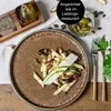 A close-up of a pasta dish on a plate, with ingredients and serving ware in the background. Produktbild-Vorschau