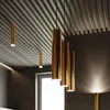Several pendant lights are hanging from a slatted ceiling in a room with a window. Voir les images du produit