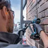 A person is using a Bosch cordless impact wrench to attach a metal bracket to a brick wall. Voir les images du produit
