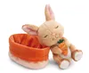 A plush bunny toy is leaning against an orange basket, holding a carrot. Produktbild-Vorschau