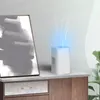An air purifier is shown on a dresser next to a piece of abstract art, with blue light emanating from the top of the purifier. Produktbild-Vorschau