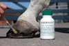 A person is applying a hoof treatment to a horse's hoof, with a bottle of the product nearby. Produktbild-Vorschau