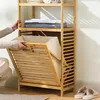 A person is interacting with a bamboo laundry shelf unit in a room. Produktbild-Vorschau
