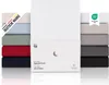 A stack of folded fitted sheets in various colors, with a white fitted sheet prominently displayed in the center, along with its packaging. Produktbild-Vorschau