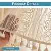 A close-up view of a white lace curtain with tassels, showing the texture and detail of the fabric. A hand is holding the curtain to show its transparency and the tassels. Produktbild-Vorschau