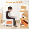 A young boy sits at a child's desk and chair set, reading a book. The image is a composite with close-up shots highlighting product features. Produktbild-Vorschau