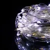A close-up of a tangled string of white LED lights on a black background. Voir les images du produit