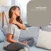 A woman is sitting on a sofa and holding her neck, indicating pain or discomfort. Anteprima dell’immagine prodotto