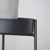 A close-up view of a black metal plant stand holding a gray pot. Produktbild-Vorschau