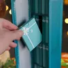 A hand is pulling a small teal box with a white ribbon design and the number 8 on it out of a teal advent calendar. Náhled obrázku produktu