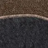 A close-up view of the edge of a round rug, showing the texture of the top and bottom layers and the stitching that joins them. Produktbild-Vorschau
