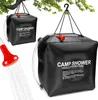 A black solar shower bag is hanging from a tree branch, with a red shower head spraying water. Náhľad obrázku produktu