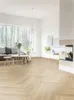 A modern living room with a herringbone wood floor, a sofa, coffee tables, and a fireplace. Produktbild-Vorschau