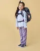 A young girl wearing a backpack and school uniform, posing for a photo. Náhľad obrázku produktu