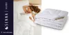A woman sleeping under a white duvet, with a folded duvet shown next to it. Produktbild-Vorschau