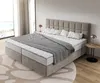 A bedroom scene with a large bed, headboard, pillows, blanket, and a side table with a lamp. Produktbild-Vorschau