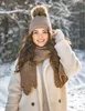 A young woman wearing a winter hat and scarf in a snowy outdoor setting. Voir les images du produit