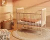 A nursery room with a wooden crib, a basket, and pillows. Anteprima dell’immagine prodotto