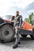 A man in workwear stands in front of an orange construction vehicle. Voir les images du produit