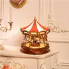 A wooden carousel music box with LED lights sits on a white table. Produktbild-Vorschau