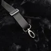 A close-up of a black strap with a silver clasp attached to a black furry surface. Náhľad obrázku produktu