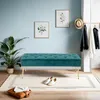 A hallway vignette with a teal velvet bench, plants, artwork, and coats on a rack. Podgląd zdjęcia produktu