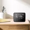 A black WiFi thermostat is placed on a wooden nightstand next to a candle and a plant. Náhled obrázku produktu