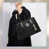 A woman is holding a black handbag. Produktbild-Vorschau