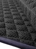 A close-up view of the textured underside of a dark gray quilted saddle pad with a dark blue binding along the edge. Produktbild-Vorschau
