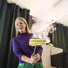 A woman is laughing while holding a steam cleaner head that is emitting steam. Podgląd zdjęcia produktu