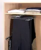 A closet interior showing a pull-out hanger rack with multiple pairs of pants and a tie hanging on it. Folded clothes are on a shelf above. Produktbild-Vorschau