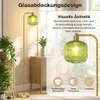 A floor lamp with a green glass shade is shown in a room with plants and furniture. The image also includes text and icons highlighting product features. Anteprima dell’immagine prodotto