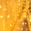 A close-up shot of warm white LED string lights hanging vertically, creating a curtain effect. Produktbild-Vorschau