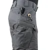 A close-up shot of the side of a person's gray tactical pants, showing several pockets and tools. Náhled obrázku produktu