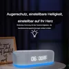 A digital alarm clock with a blue light base and a framed picture in the background. Produktbild-Vorschau