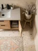 Aufsicht auf einen stehenden Badschrank 60x60 cm mit Wiener Geflecht, platziert auf einem runden Juteteppich vor einem modernen Waschtisch._#sku_SAFWL6.876# Produktbild-Vorschau