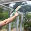 A person is cleaning a window with a squeegee and cleaning solution. Produktbild-Vorschau