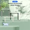 A collage of different colored height-adjustable desk frames displayed on a tiered green background with decorative foliage. Produktbild-Vorschau