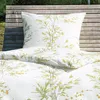 A close-up view of bedding with a floral pattern, placed on a wooden bench outdoors. Produktbild-Vorschau