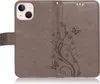 A close-up view of a brown flip phone case with a floral and butterfly embossed design. Produktbild-Vorschau