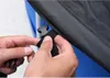 A close-up of hands securing a buckle on a black cover, with a blue surface visible underneath. Anteprima dell’immagine prodotto